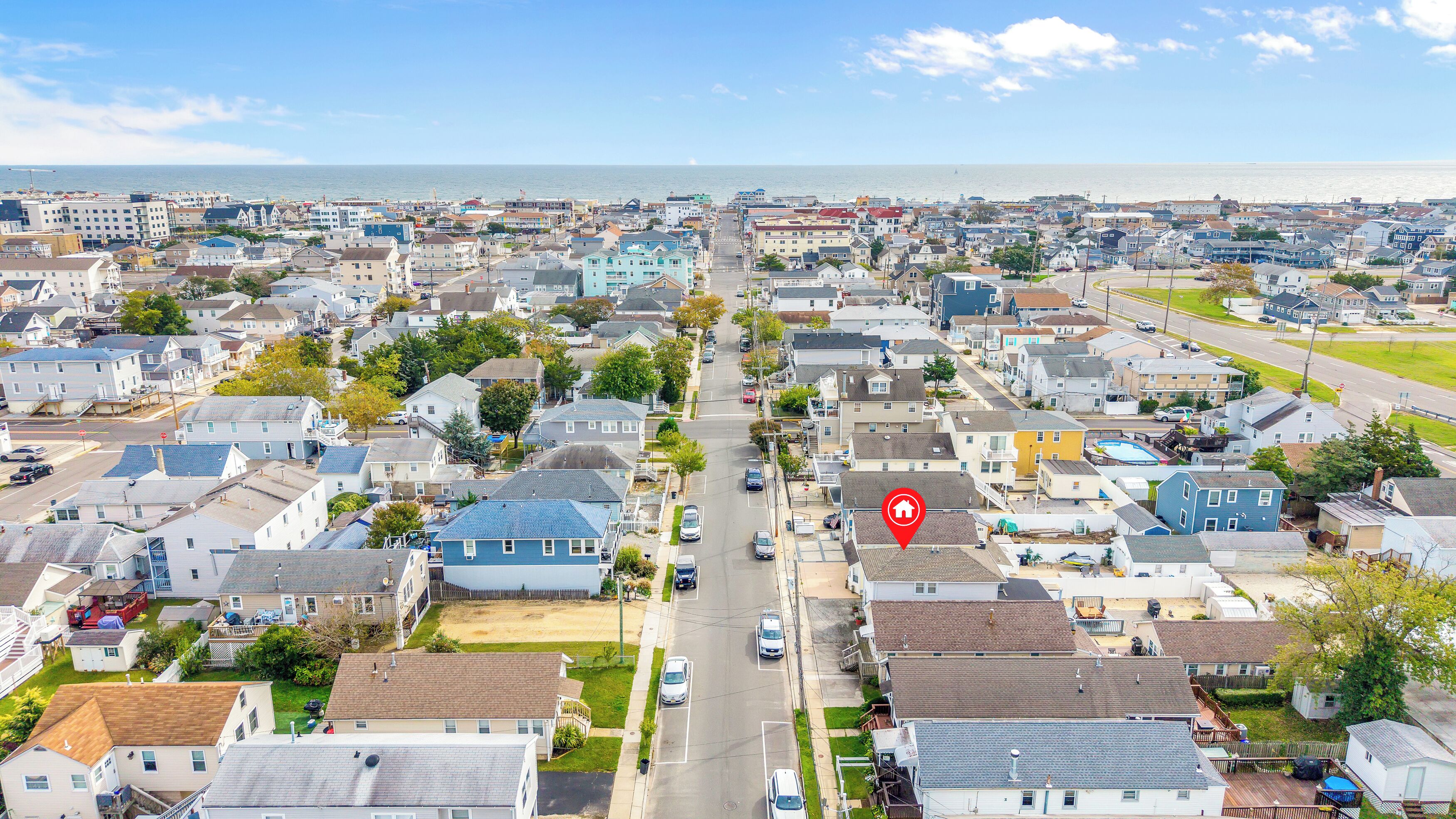 A residential area with houses, streets, and a body of water in the background.