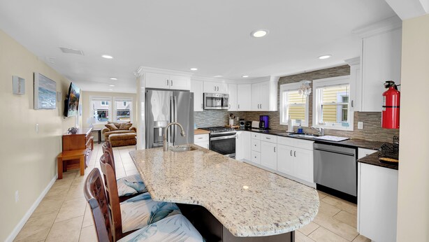 A modern kitchen with white cabinets, a granite countertop, and stainless steel appliances. - ICONIC SEASIDE HEIGHTS BEACH HOUSE (Seaside Heights)