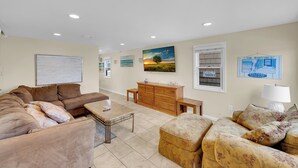 A living room with a brown sofa, a wooden cabinet, and a painting of a sunset. - ICONIC SEASIDE HEIGHTS BEACH HOUSE (Seaside Heights)