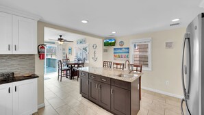 A modern kitchen with a central island, a dining area, and a view to the outside. - ICONIC SEASIDE HEIGHTS BEACH HOUSE (Seaside Heights)