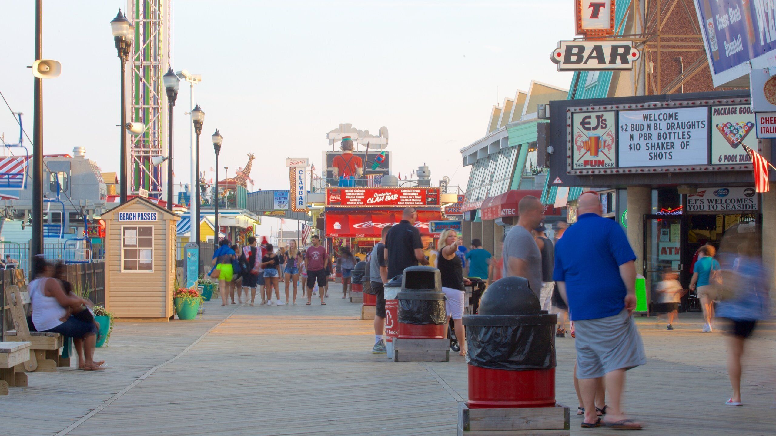 A boardwalk with various shops and signs, including a bar and a restaurant.