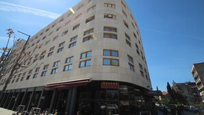 Un hotel de varios pisos con fachada curva, ventanas grandes y un letrero que dice "KAVANA EMANUEL HOTEL".