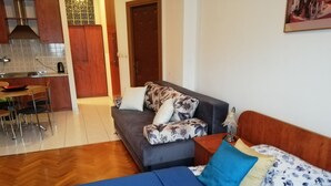 Una habitación con sofá, cama, mesa de comedor y zona de cocina.