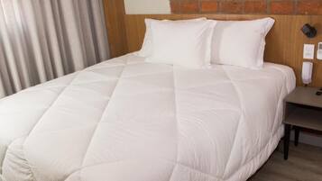 A hotel room with a large bed, a wooden headboard, a nightstand with a phone, and a brick wall.