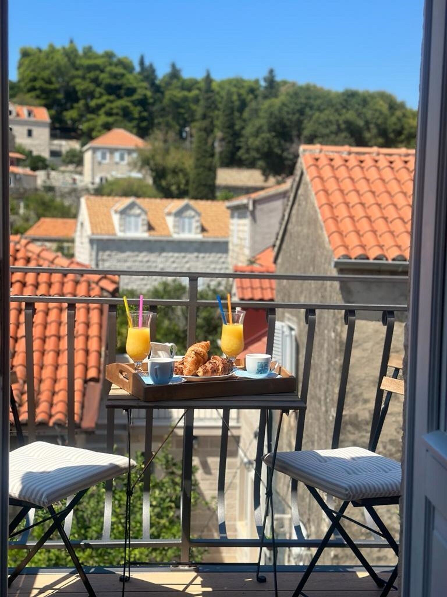 Ein Balkon mit Frühstücksangebot, darunter Croissants, Kaffee und Orangensaft.