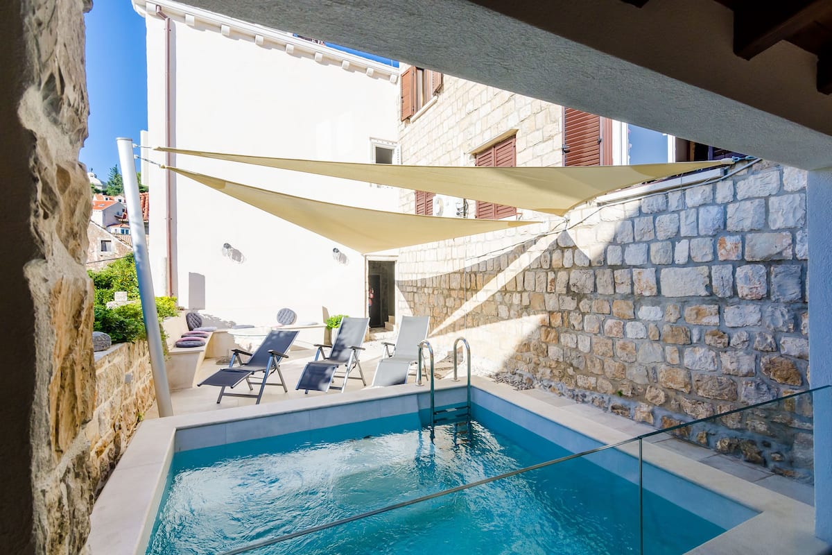 Ein Poolbereich mit Liegestühlen und einer Steinmauer.