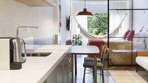 Eine moderne Küche mit Einbauofen, ein Essbereich mit Tisch und Stühlen sowie ein Wohnbereich mit Sofa und Hängematte.