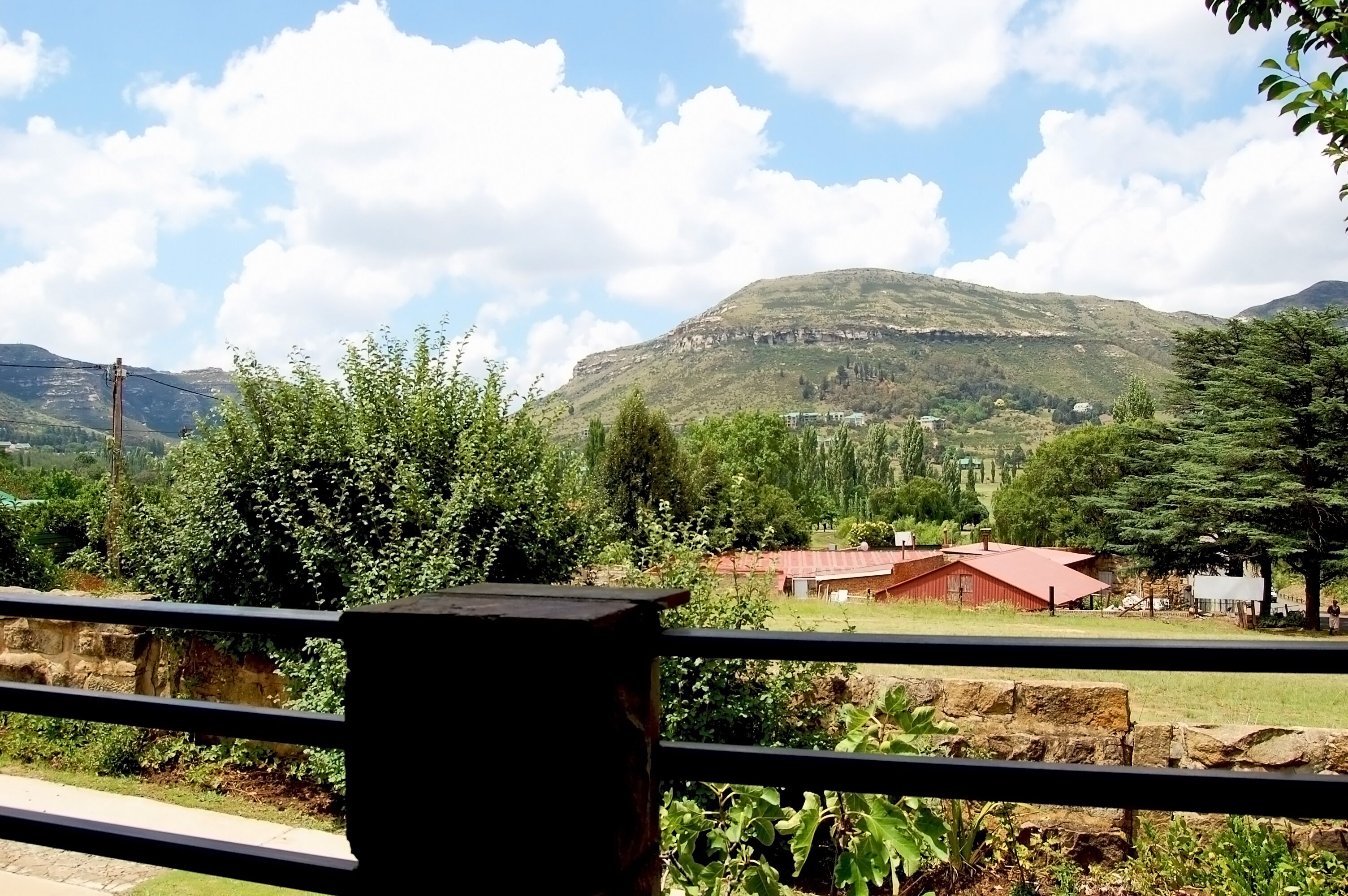 A rural landscape with a mountain, trees, and a red-roofed building.
