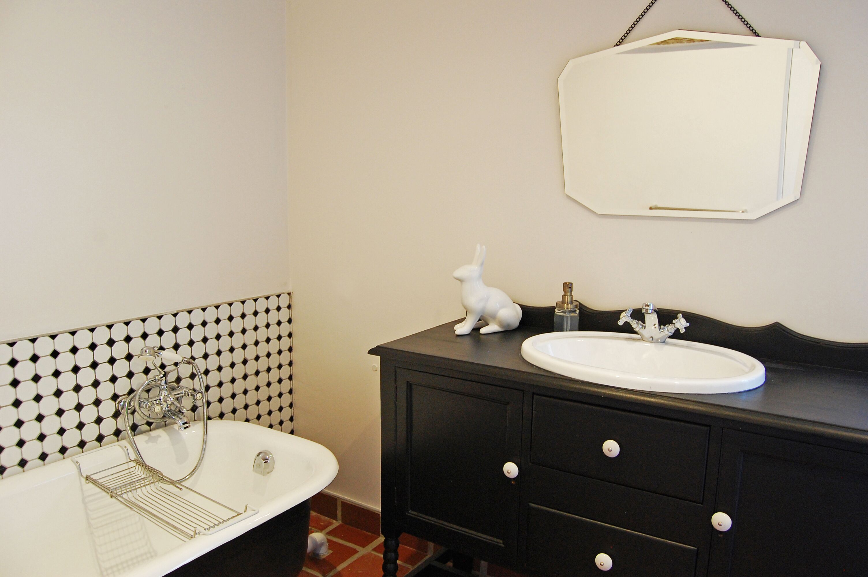 A bathroom with a white sink, black vanity, and a white wall-mounted mirror.