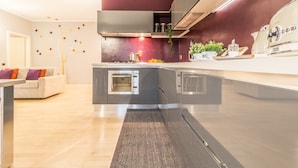 A modern kitchen with a central island, built-in oven, and stainless steel appliances. - Family Apartments Verdi (Trento)