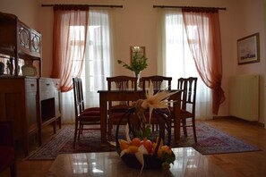 A dining area with a wooden table, chairs, and a fruit basket.