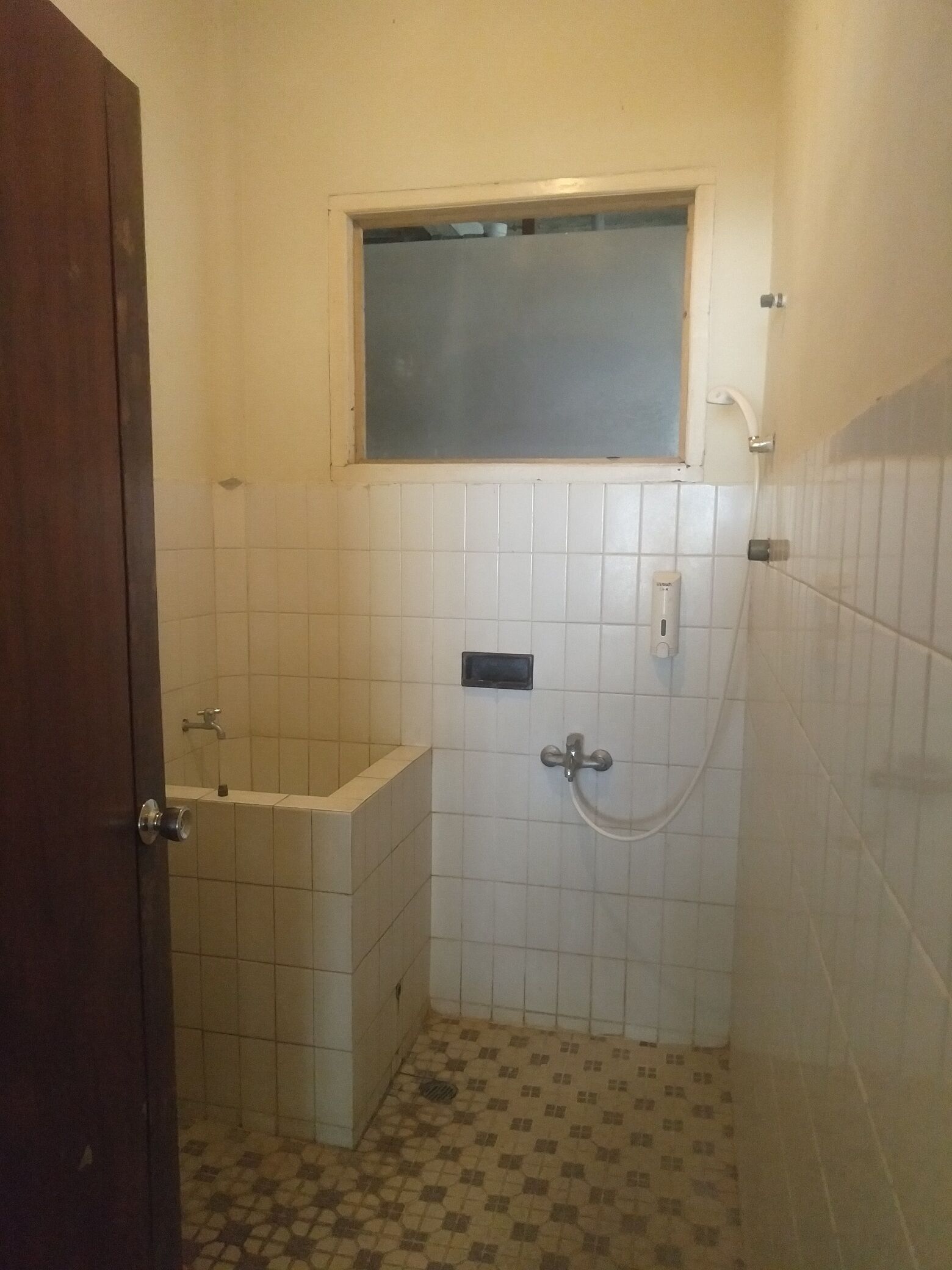 A small bathroom with a bathtub, a shower, and a window above the bathtub.