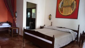 A bedroom with a wooden bed, a nightstand, a lamp, and a red abstract painting on the wall. - Bunga Ayu Seaside Resort (Pelabuhan Ratu)