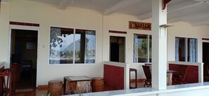 Habitación de hotel con ventanas amplias, una mesa de madera y un panel decorativo rojo en la pared.