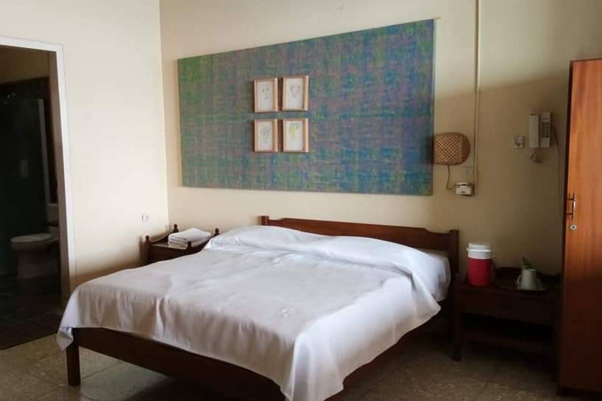A hotel room with a bed, a bathroom, and a wall with framed pictures.