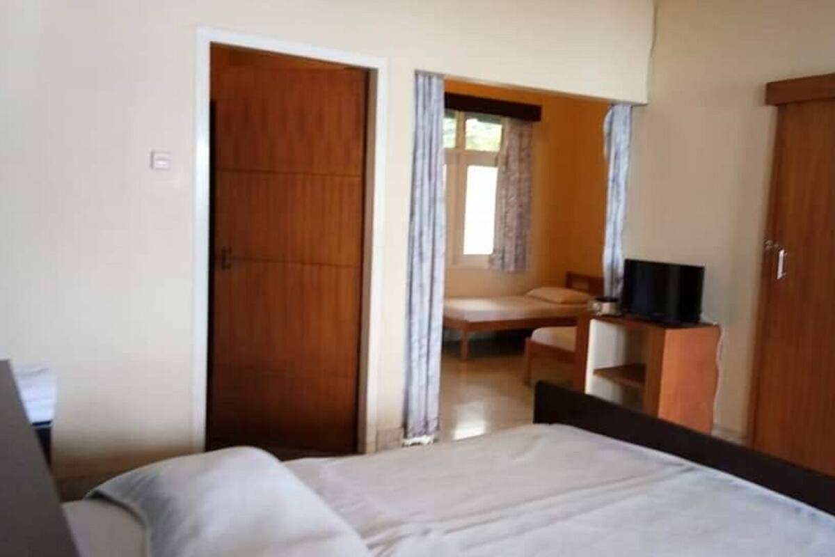 A hotel room with a bed, a desk, and a television.