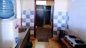 A kitchen with a water dispenser, a sink, a stove, and a tiled backsplash. - Bunga Ayu Seaside Resort (Pelabuhan Ratu)