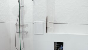 Une salle de bain moderne équipée d’une douche, de toilettes et d’un petit lavabo.