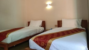 A hotel room with two single beds, each with a wooden headboard and white bedding. There is a wall-mounted light fixture above the beds. - Sunrise Square Motel (Yangon)