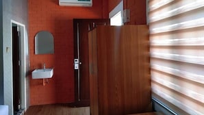 A bathroom with a wooden vanity, a mirror, a sink, and a door. - Sunrise Square Motel (Yangon)
