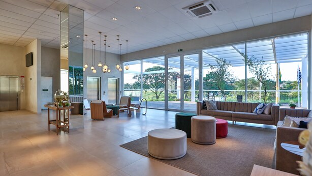 En rymlig entréhall med modern design, med en stor sittgrupp, en receptionsdisk och stora fönster som ger utsikt över omgivningarna.