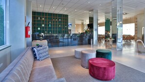 En modern entréhall med en sittgrupp, en receptionsdisk och ett stort fönster.