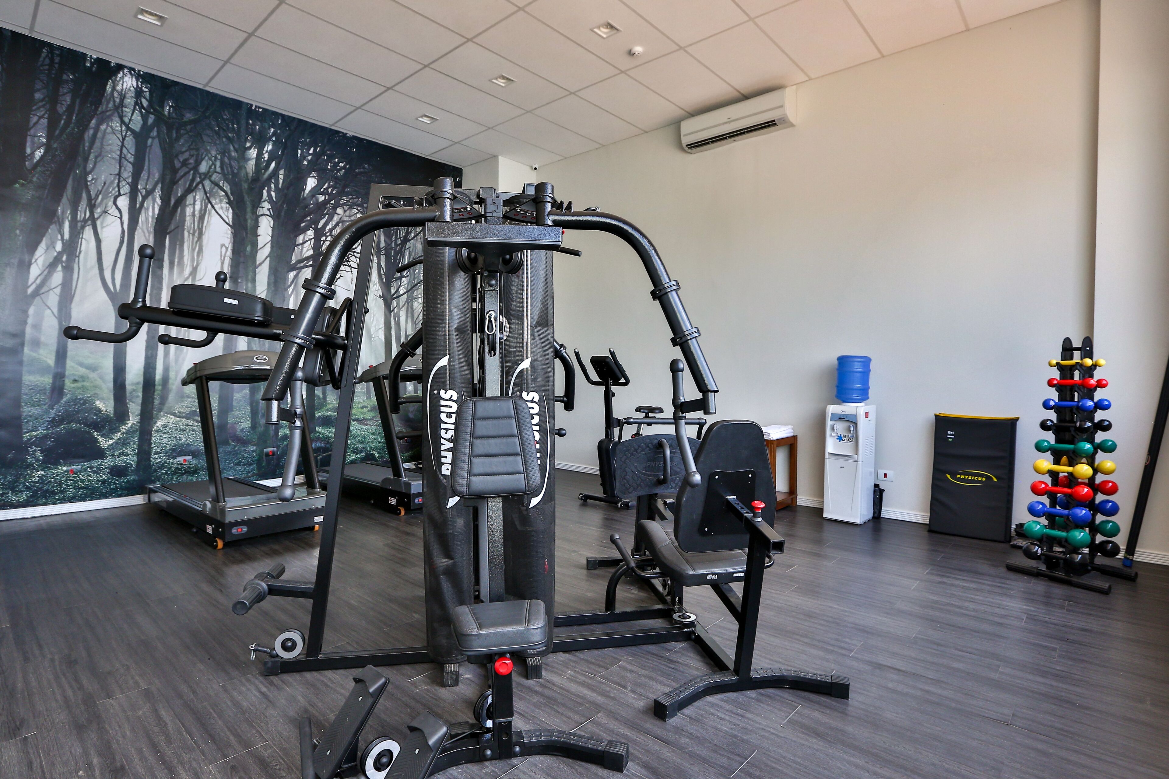 A gym with various exercise equipment, including a treadmill, weight machines, and a squat rack.
