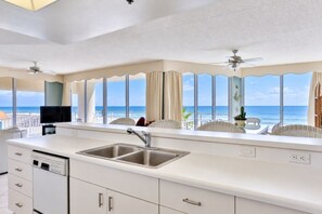 A kitchen with a large window, a sink, and a ceiling fan. - Surf And Racquet 101 3 Bedroom Condo by RedAwning (New Smyrna Beach)