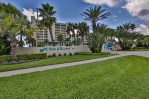 A hotel sign with the name 'Surf & Racquet' and a building in the background. - Surf And Racquet 101 3 Bedroom Condo by RedAwning (New Smyrna Beach)