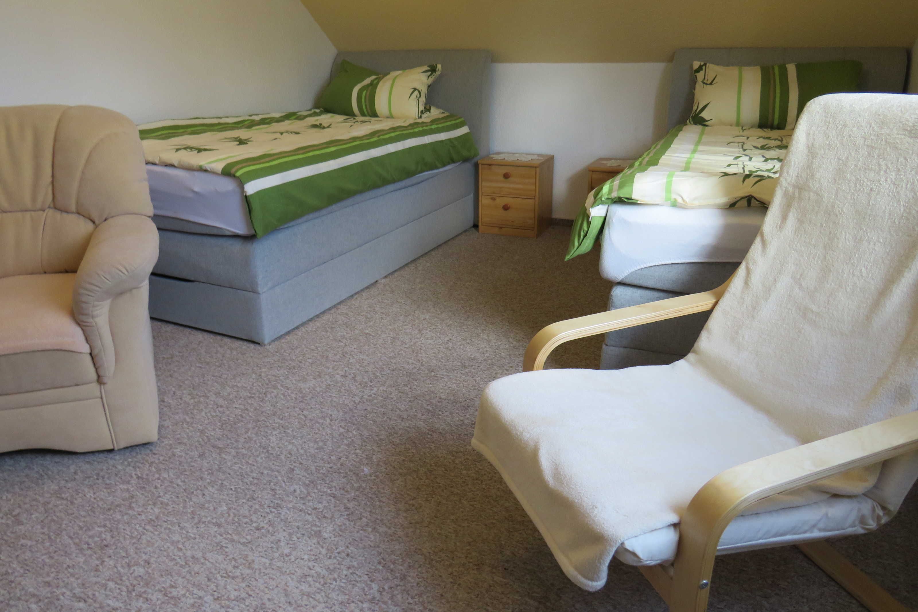 Un dormitorio con dos camas, una silla y una mesita de noche.