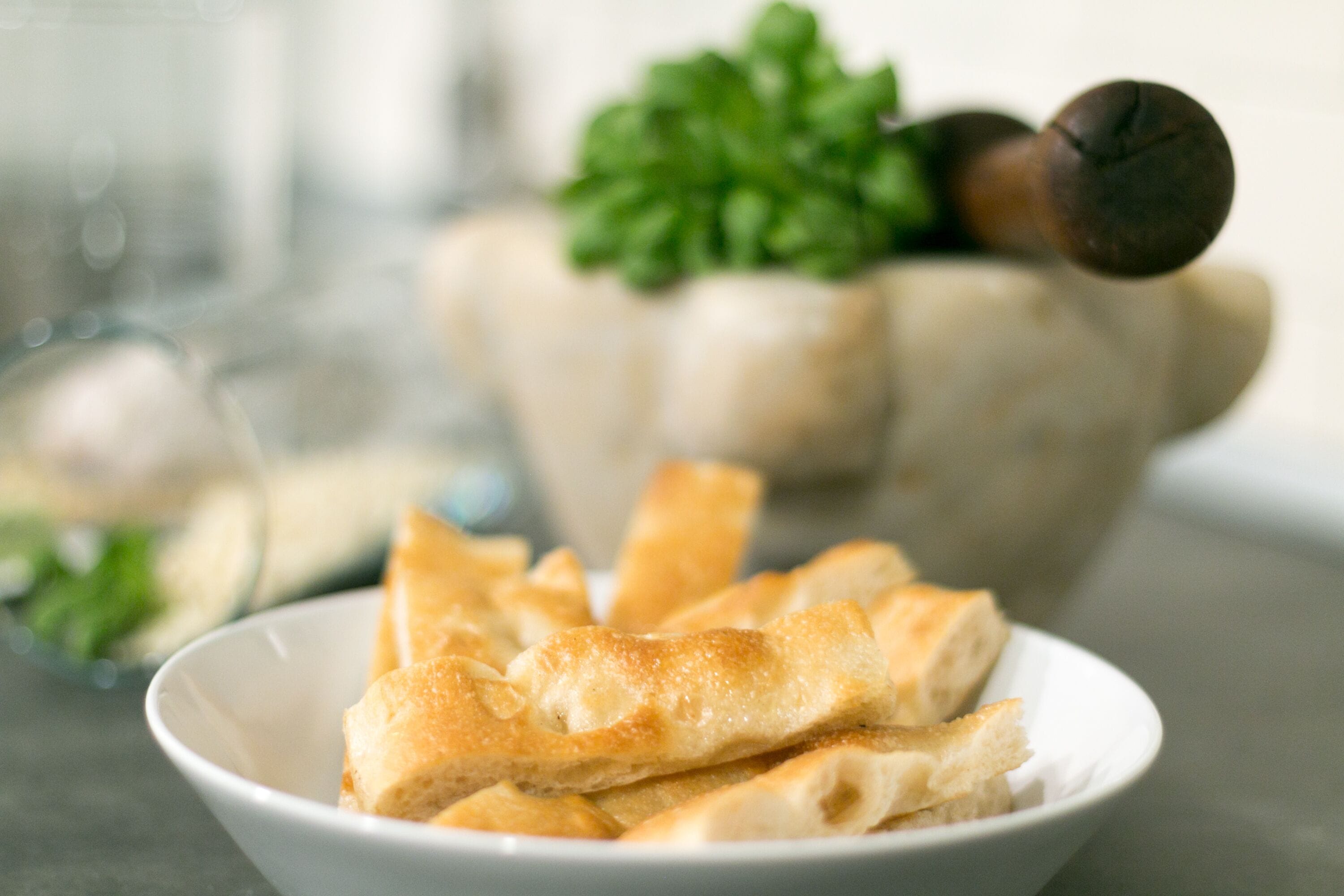 A bowl of flatbread with a green garnish in the background.
