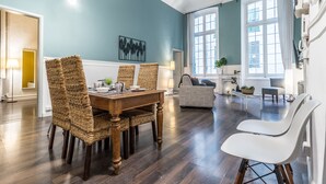 Un salón espacioso con una mesa de comedor, sillas de mimbre y un sofá.