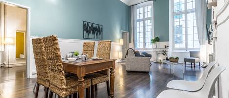 A spacious living room with a dining table, wicker chairs, and a sofa.