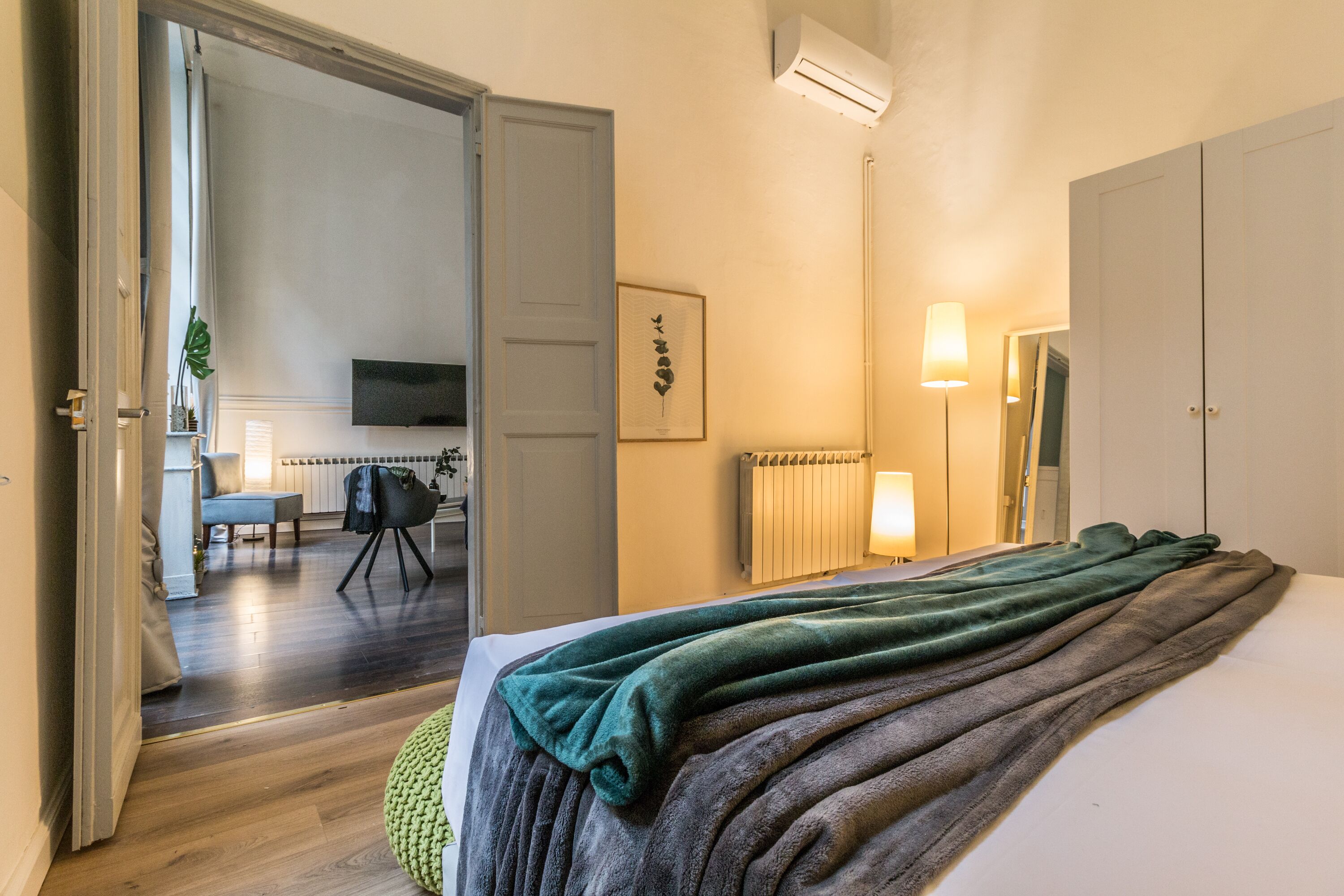 Ein Hotelzimmer mit einem Bett, einem Schreibtisch, einem Sessel, einem Fernseher und einer Heizung.