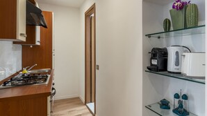 A kitchen with a stove, cabinets, and a glass shelf with kitchen appliances. - Via degli Avignonesi (Rome)