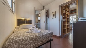 Un dormitori amb llit, taula de nit, armari i bany visible a través d'una porta oberta.