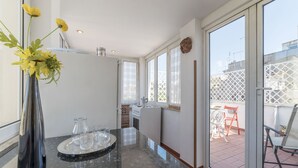 Una cuina moderna amb taulell de marbre, un ram de flors grogues i vista al pati exterior.