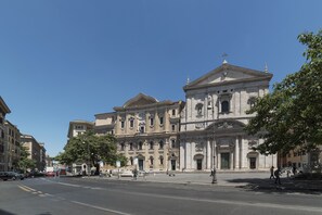 A historic building with classical architecture, a wide street, and pedestrians.