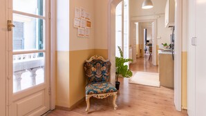 A hallway with a wooden floor, a decorative chair, a potted plant, and framed certificates on the wall. - Family Apartments Angeli (Genoa)