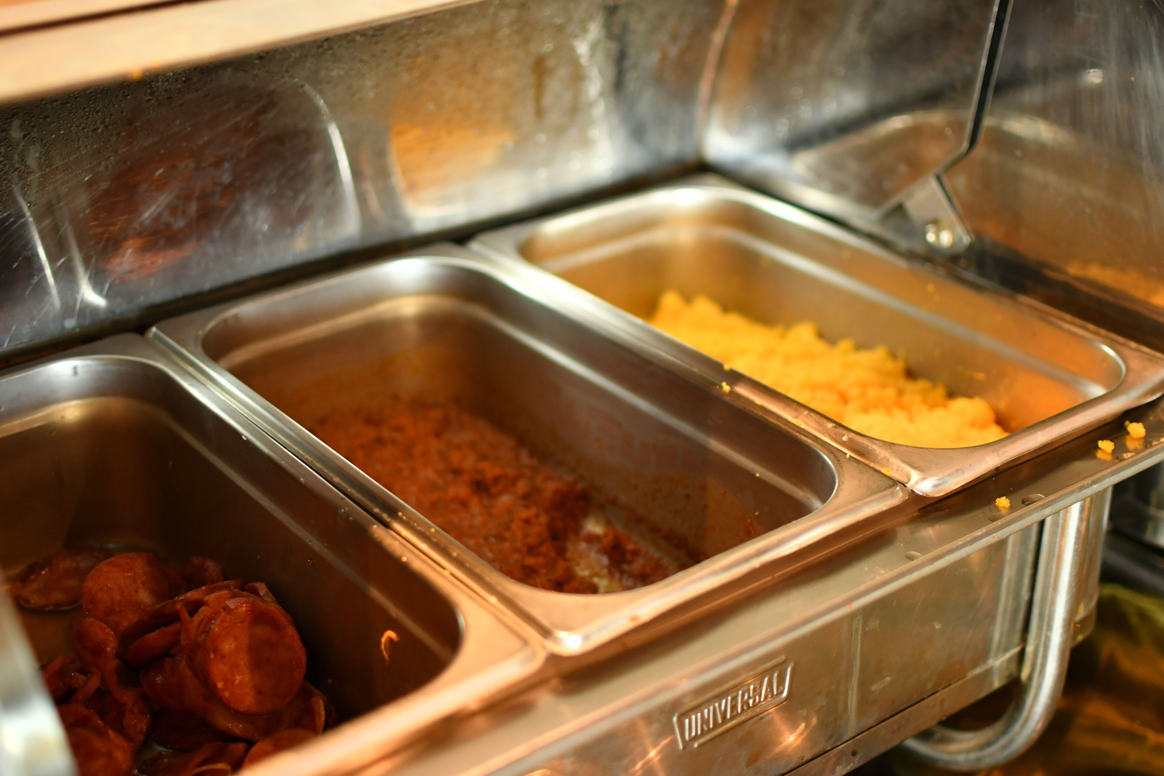 Un bufé con diversas opciones de comida, incluyendo un plato de carne, puré de papas y un pastel de carne.