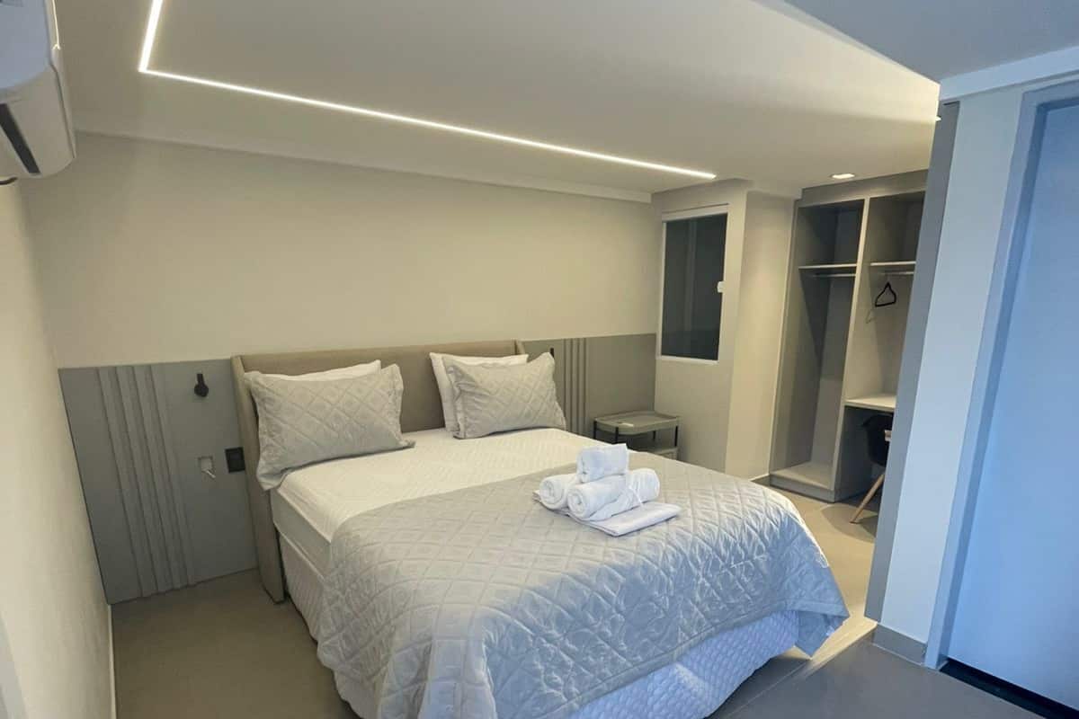 Habitación de hotel moderna con una cama grande, una mesita de noche, un armario y un vestidor.