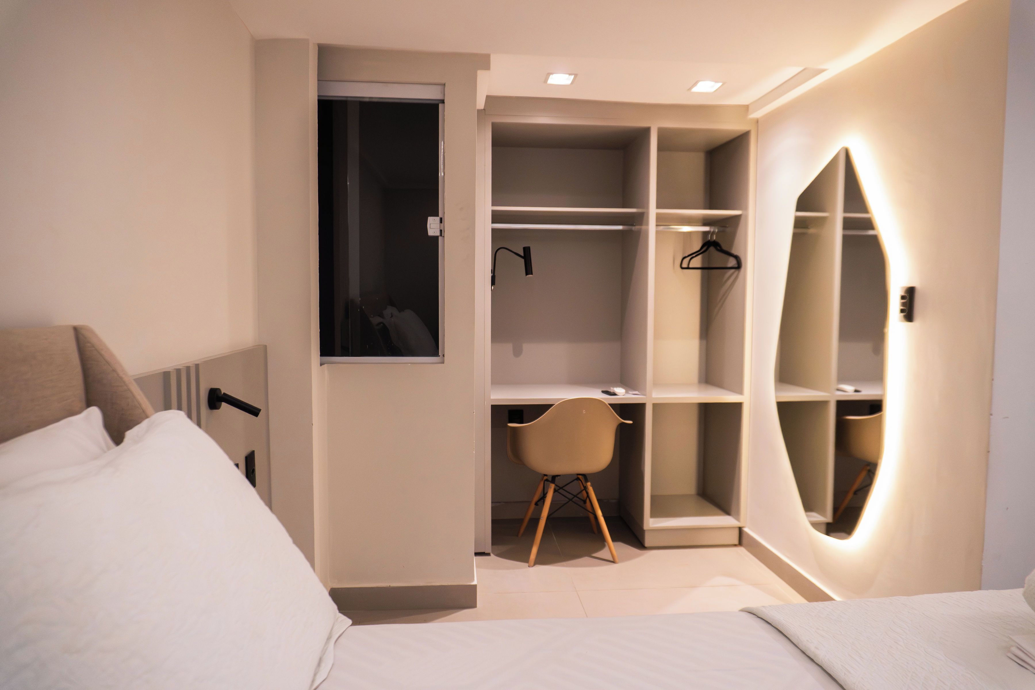 A modern bedroom with a bed, a desk, and a walk-in closet.