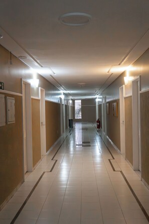 A long, narrow hallway with doors on both sides, a fire extinguisher, and a trash bin. - Troodon Park Hotel (Sousa)