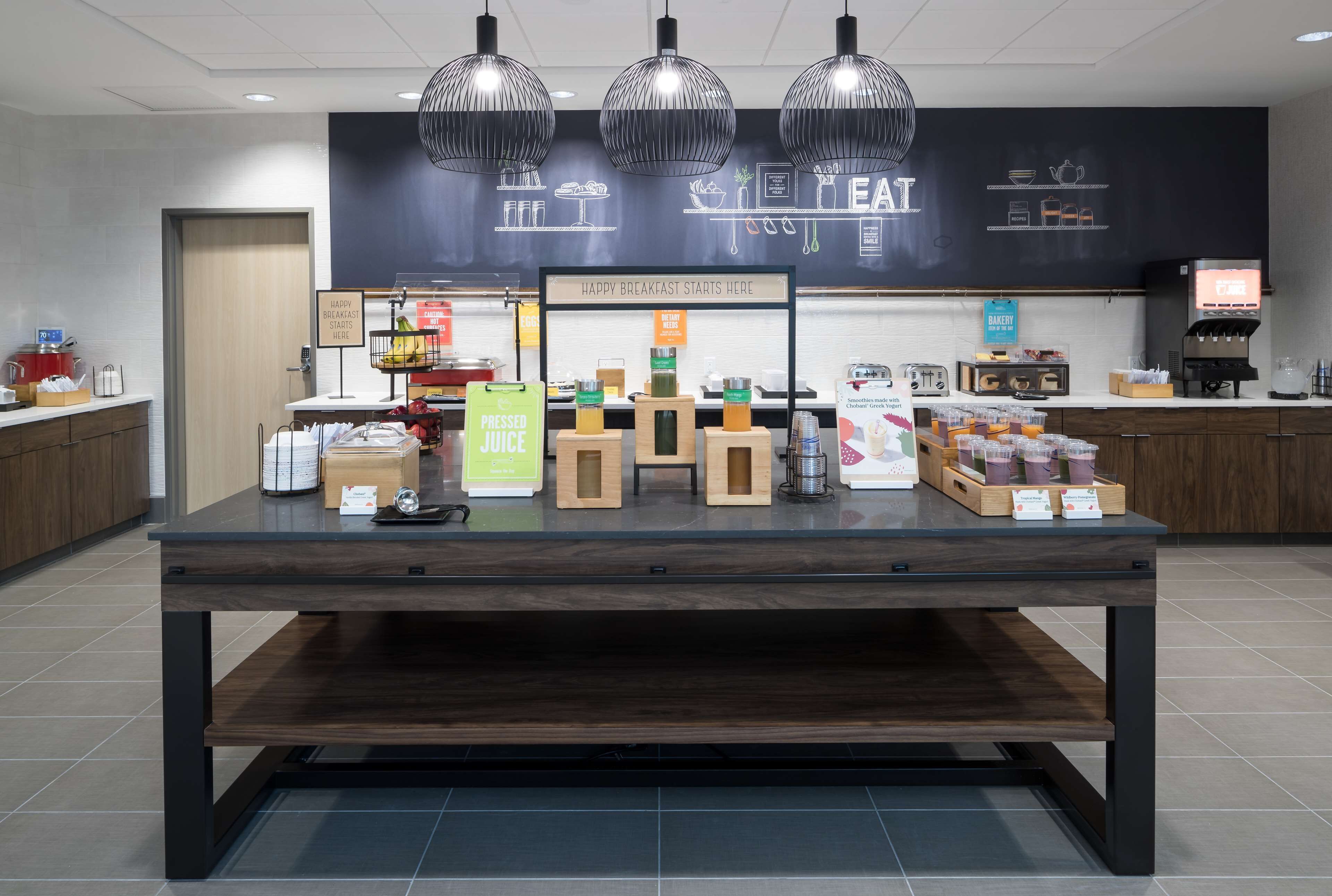A breakfast area with a counter displaying various food items and a sign indicating the start of breakfast.