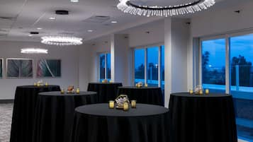 A conference room with round tables, black tablecloths, and decorative candle holders.