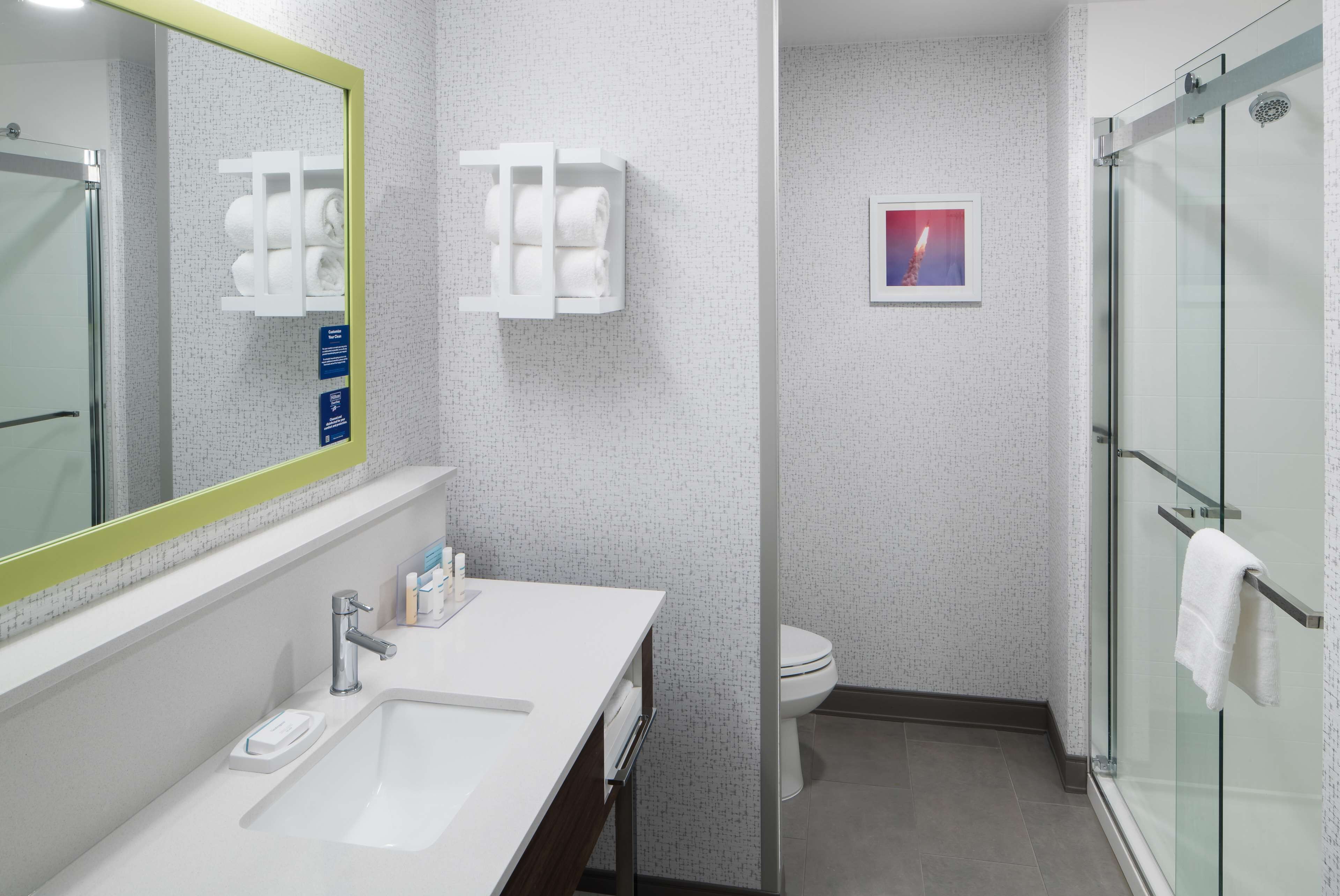 A modern bathroom with a large mirror, white sink, and glass shower enclosure.