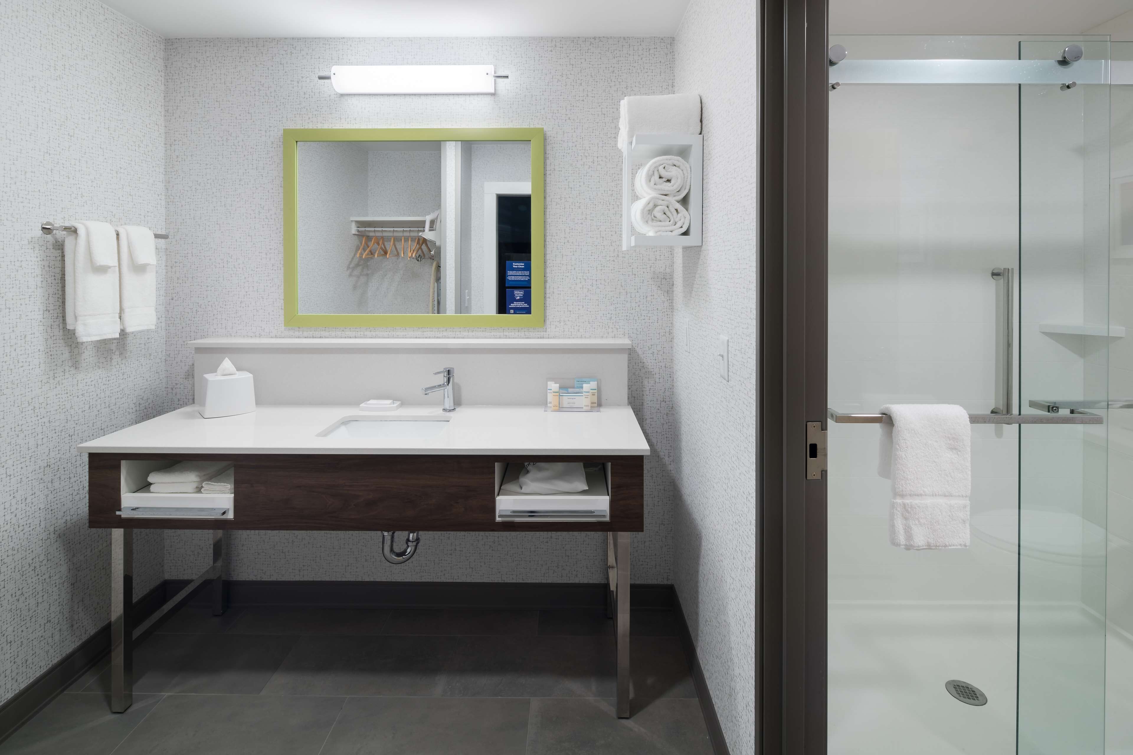 Un baño moderno con lavamanos blanco, espejo y cabina de ducha de vidrio.