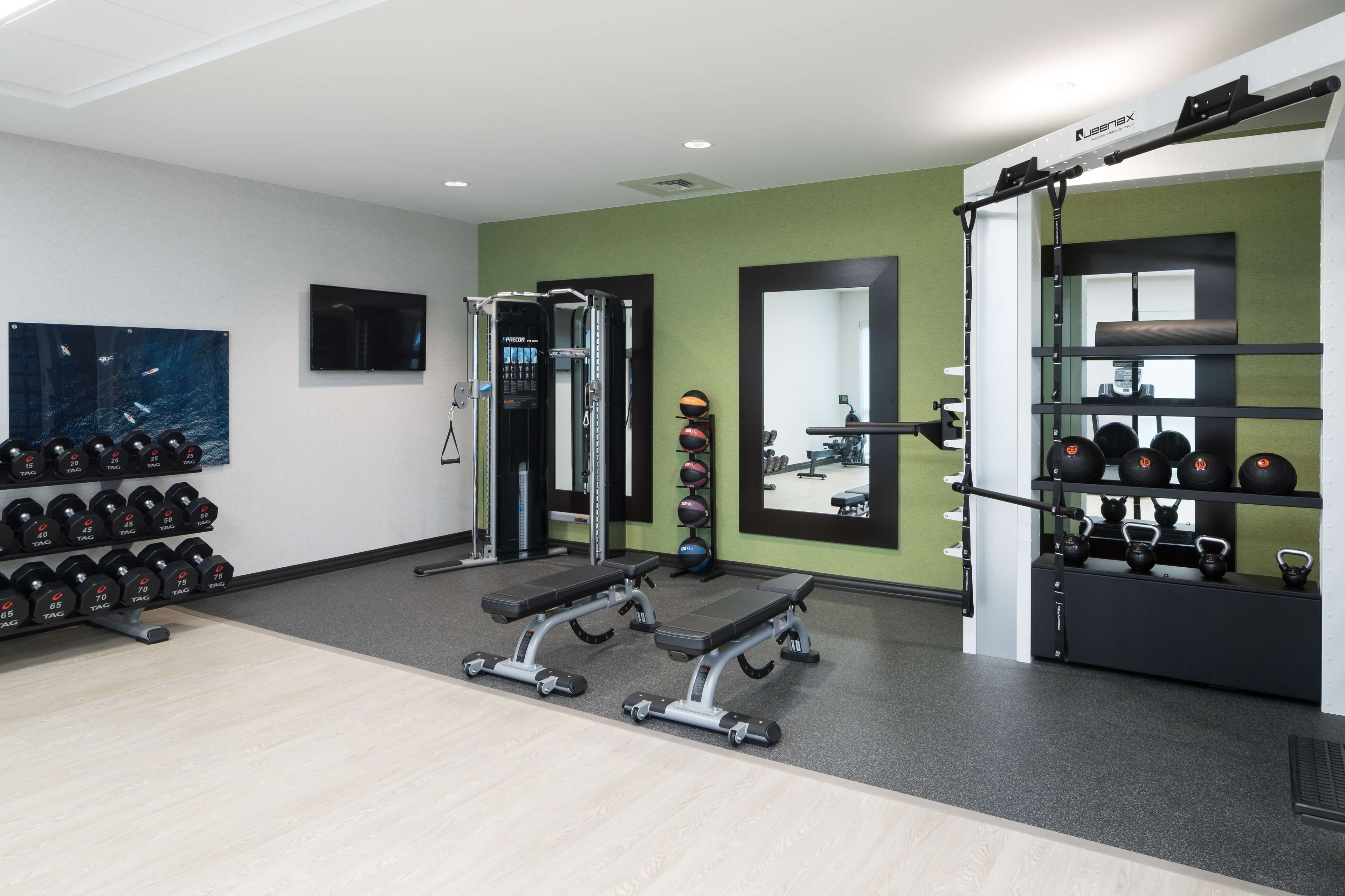 Ein Fitnessraum mit Gewichtstrainern, Kurzhanteln und Trainingsbällen.