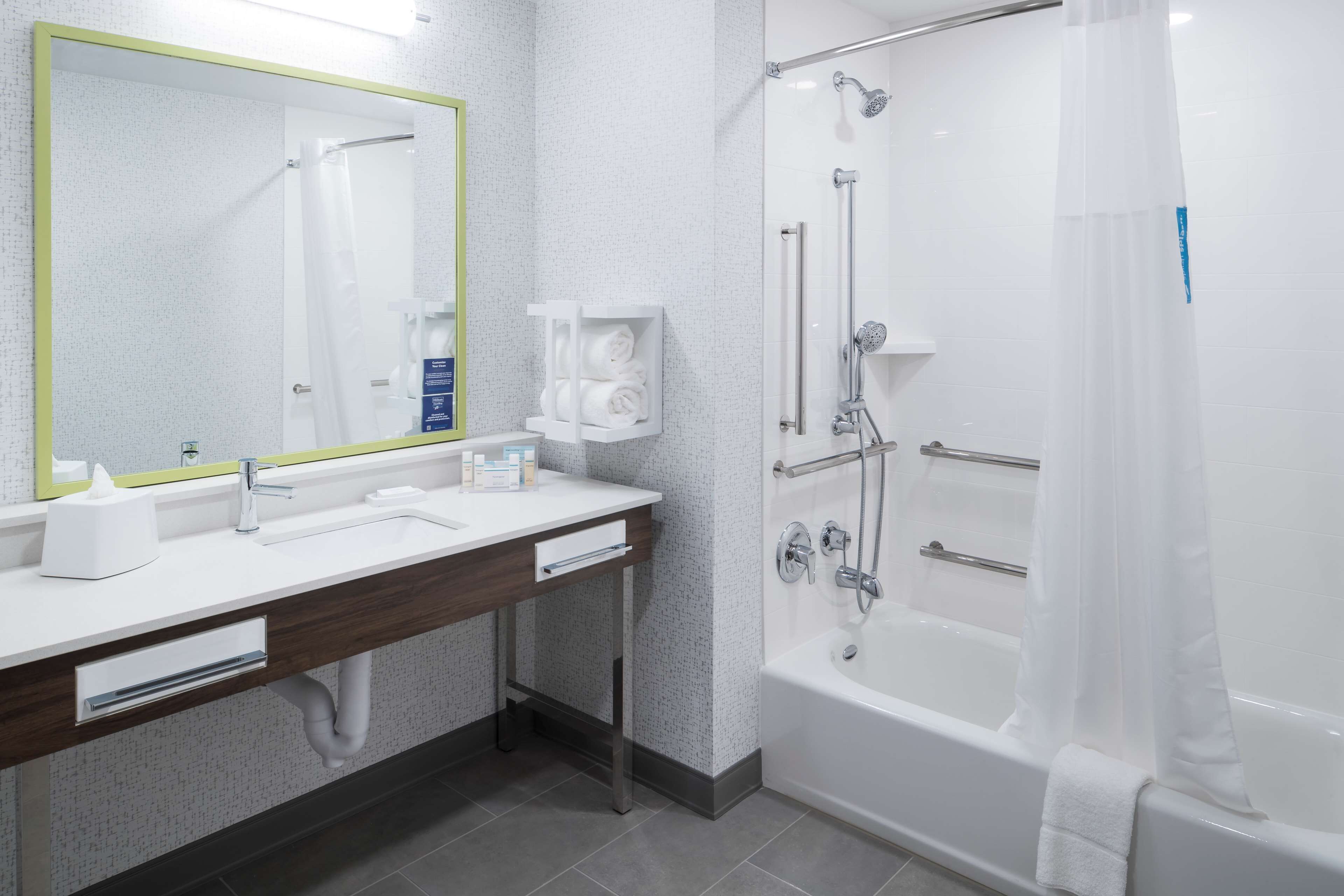 A modern bathroom with a white sink, mirror, and bathtub.