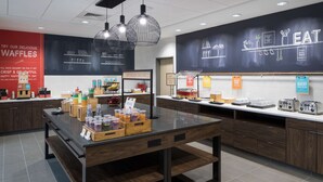A modern kitchen area with a central island, various food items, and a chalkboard wall with the word "EAT".
